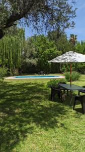 una mesa con sombrilla junto a una piscina en Loren House en Luján de Cuyo