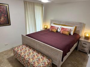 a bedroom with a large bed with a bench next to a window at River Gum Apartment in Diddillibah