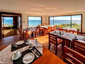a dining room with tables and chairs and the ocean at Hotel Bután Coronel in Coronel