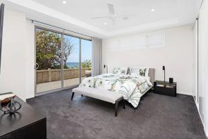 een slaapkamer met een bed en een groot raam bij Beachfront Bliss in Shellharbour