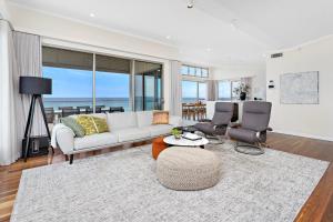 een woonkamer met een witte bank en stoelen bij Beachfront Bliss in Shellharbour