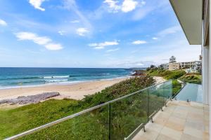 uitzicht op het strand vanaf het balkon van een huis bij Beachfront Bliss in Shellharbour