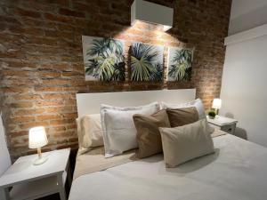 1 dormitorio con cama blanca y pared de ladrillo en Cabin studio Cerca del mar - José Ignacio, en José Ignacio
