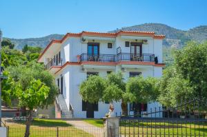 una gran casa blanca con árboles delante de ella en Pension Assos, en Koinira