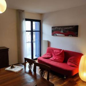 sala de estar con sofá rojo y ventana en lL NIDO IN CITTÀ, en Trento