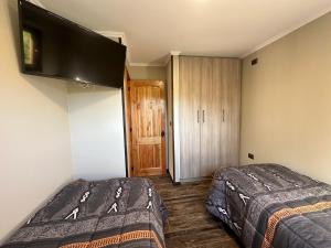 1 dormitorio con 2 camas y TV en la pared en Mirabosque aparment Ejecutivos 6 en Osorno