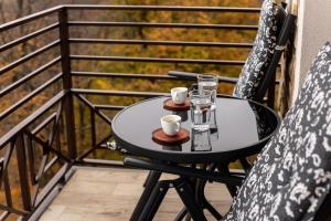 uma pequena mesa numa varanda com duas canecas e copos em Apartman Stankovic Milmari Resort em Kopaonik