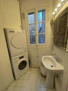 a bathroom with a washing machine and a sink at Le Cœur de l’Île Saint-Louis, you will love it! in Paris