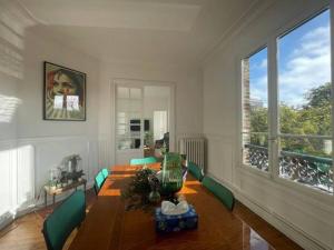 a living room with a wooden table and green chairs at Le Cœur de l’Île Saint-Louis, you will love it! in Paris