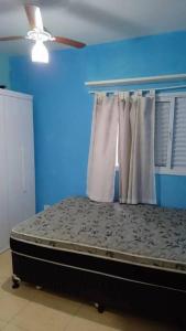 - une chambre bleue avec un lit et un ventilateur de plafond dans l'établissement Casa com piscina perto da praia, à Caraguatatuba