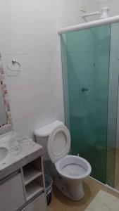 La salle de bains est pourvue de toilettes et d'une douche en verre. dans l'établissement Casa com piscina perto da praia, à Caraguatatuba