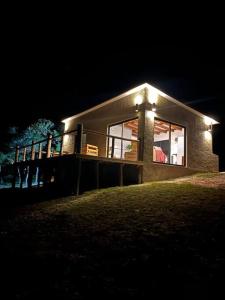 a house with lights on the side of it at night at La Luna, casa mágica en sierras! in Villa Serrana