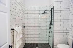 baño de azulejos blancos con ducha y aseo en Terrace Suites en Callander
