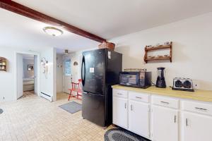uma cozinha com um frigorífico preto e armários brancos em Evans Green em Northfield