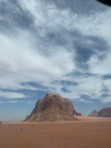 Wadi Rum desert Mohammed في وادي رم: جبل في الصحراء تحت سماء غائمة