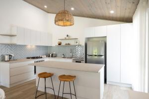 a kitchen with white cabinets and a counter with stools at Kaia's Beach Retreat in Mollymook