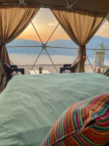 a bed in a tent with a view of the beach at Pacucha Glamping in Andahuaylas