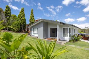 a white house with a yard at Kaia's Beach Retreat in Mollymook