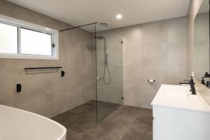 a bathroom with a shower and a sink and a tub at Kaia's Beach Retreat in Mollymook +18 photos