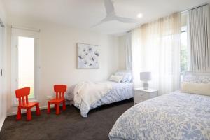 a bedroom with two beds and two red chairs at Kaia's Beach Retreat in Mollymook