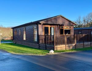 a small wooden house with a fence in the grass at Charming Hazel Lodge - Relaxing Devon Getaway in Chudleigh