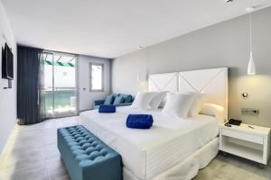 1 dormitorio con 1 cama blanca grande y 1 sofá azul en Barceló Teguise Beach - Adults Only, en Costa Teguise