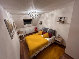 um quarto com uma cama amarela e um lustre em LE NOUVEAU VAUBAN em Colmar