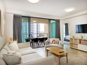 a living room with white furniture and a dining room at Broadbeach on the park 2-Bedroom in Gold Coast