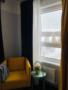 a yellow chair and a table in front of a window at Mežaparka apartamenti in Jēkabpils