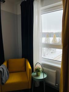 une chaise jaune et une table devant une fenêtre dans l'établissement Mežaparka apartamenti, à Jēkabpils