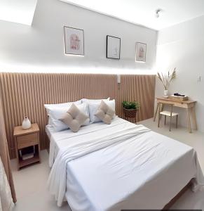 um quarto com uma cama grande com lençóis brancos e almofadas em Dreamy Aesthetic Suite in City Center em Cebu