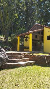 una casa con columnas amarillas y escaleras en un patio en Sítio Vila de Santa Barbara, en Caeté
