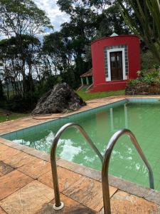 una piscina con una casa roja y un edificio rojo en Sítio Vila de Santa Barbara, en Caeté