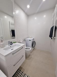 een witte badkamer met een toilet en een wastafel bij Palace Hils in Boekarest