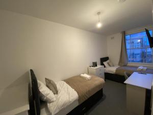 a room with two beds and a desk and a window at Cosy 3BD Guesthouse w/ Private Bathrooms in Northampton