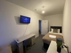 a bedroom with a bed and a tv on the wall at Cosy 3BD Guesthouse w/ Private Bathrooms in Northampton