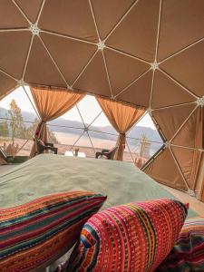 a bed in a tent with a view of the desert at Pacucha Glamping in Andahuaylas