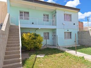 una casa bianca con le scale di fronte di Departamentos Ariadna a Comodoro Rivadavia