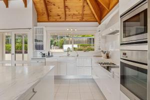 a kitchen with white cabinets and a wooden ceiling at Gulf View Retreat - 11 Hewett Close in Normanville
