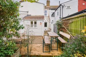 une terrasse en bois avec deux bancs et une table dans l'établissement Host & Stay - Sparrows Nest, à Whitstable