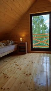 Dormitorio con ventana grande en una cabaña de madera en Domki Dębowe Wzgórze en Potok Złoty