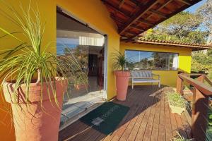 une maison jaune avec des plantes en pot sur une terrasse dans l'établissement Pousada MAR João Fernandes, à Búzios