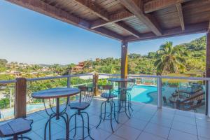 a balcony with bar stools and a view of the pool at Pousada MAR João Fernandes in Búzios
