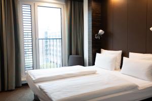 a bedroom with a large bed with a large window at Motel One Düsseldorf Hauptbahnhof in Düsseldorf