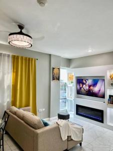 uma sala de estar com um sofá e uma televisão de ecrã plano em BYRD’S Oasis Apartment em Kingston