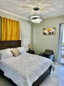 a bedroom with a large white bed and a chandelier at BYRD’S Oasis Apartment in Kingston