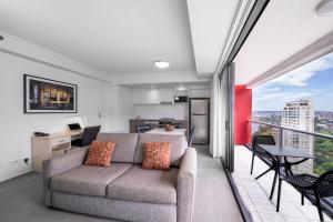 a living room with a couch and a balcony at Oaks Brisbane on Felix Suites in Brisbane