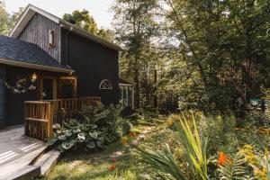 a black house with a deck and a garden at Auberge Yoga Salamandre in Lac-Brome