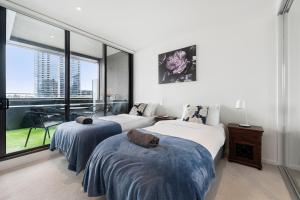a bedroom with two beds and a large window at Melbourne Docklands Riverside Views in Melbourne
