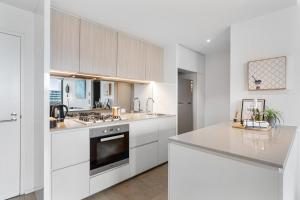 a white kitchen with white cabinets and appliances at Melbourne Docklands Riverside Views in Melbourne